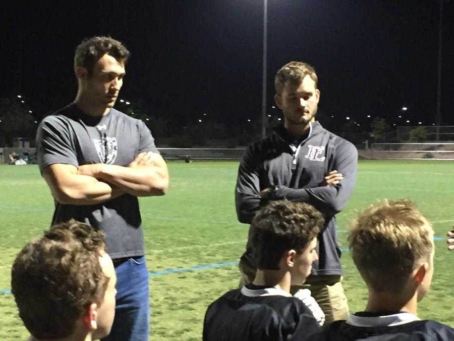 Photo caption: John Greeley and Max Schmidt wait to address the offense and defense as Head Coach James Gravitt addresses the team as a whole. Photo by Alicia Loh