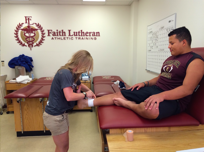 Photo caption: New trainer wraps Josh Rodriguez's ankle after an injury